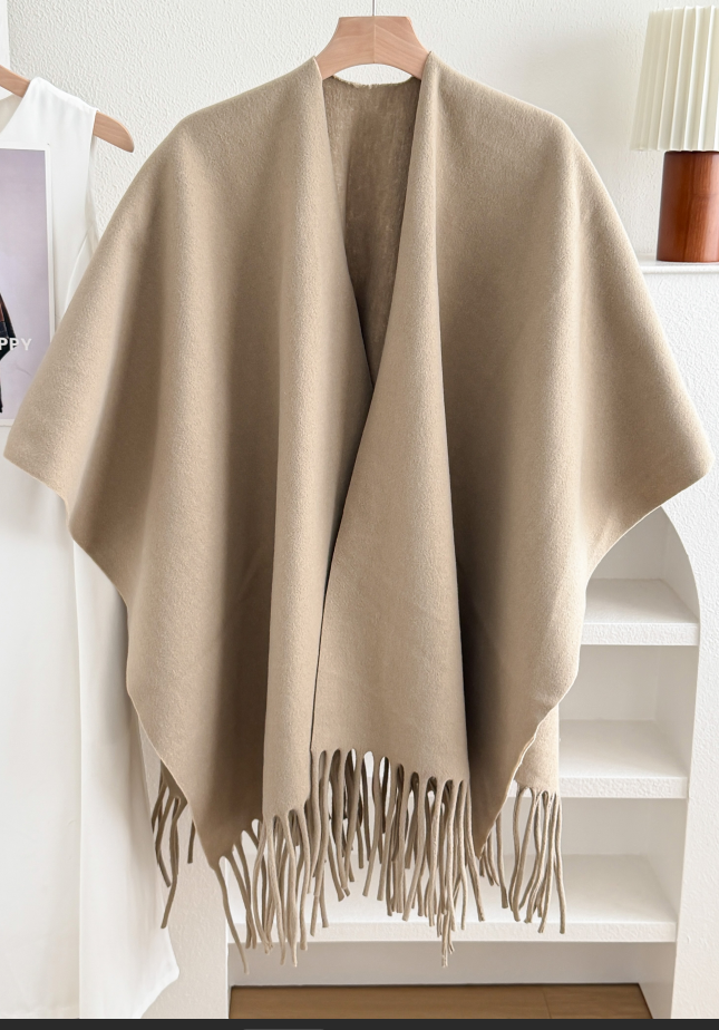 Soft sand-colored fringed shawl draped on a hanger